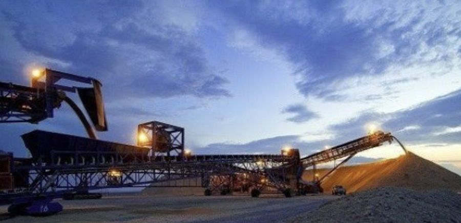 Stacker and conveyor at dusk building a stockpile